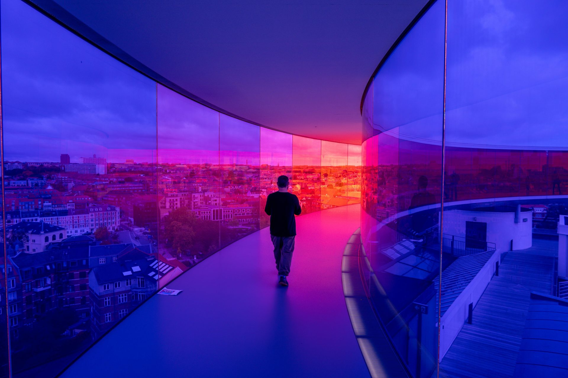 Man walking on curved walkway with colorful glass walls